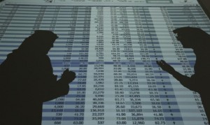 The shadows of investors and speculators are seen cast on a screen as they monitor stock prices at the FALCOM investment bank in Riyadh