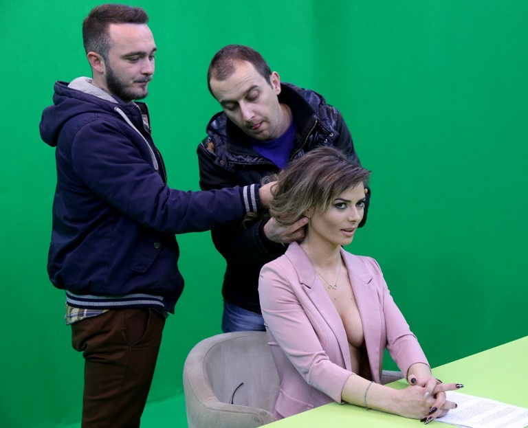 TO GO WITH AFP STORY BY BRISEIDA MEMA A picture taken on January 14, 2016 shows technicians adjusting the microphone of presenter Greta Hoxhaj, 24, prior her news edition on Zjarr TV (fire tv) in Tirana. Faced with tough competition to win over audiences, an Albanian TV channel is taking a literal approach towards giving viewers the "naked" truth -- by employing almost-topless newsreaders. Wearing open jackets, and nothing underneath, the young women reading the headlines on Zjarr TV are an unprecedented sight in the conservative Balkan country, where they first appeared on television and internet screens last year. / AFP / GENT SHKULLAKU