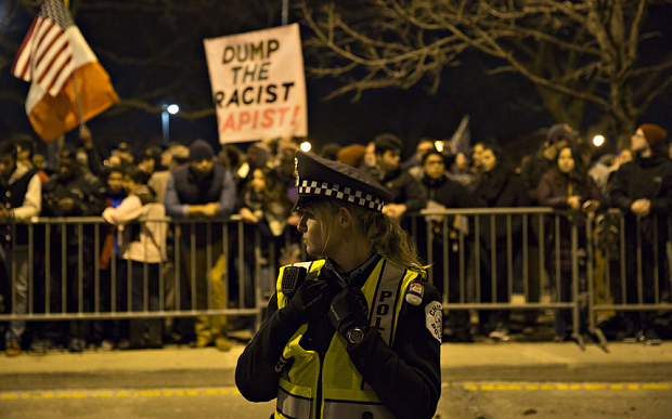 A police officer stands near a group of demonstrators outside a canceled campaign event with Donald Trump, president and chief executive of Trump Organization Inc. and 2016 Republican presidential candidate, in Chicago, Illinois, U.S., on Friday, March 11, 2016. Trump canceled a Friday evening rally in Chicago after his campaign met with law enforcement and concluded it wasn't safe to proceed amid extensive protests in the heavily Democratic city. Photographer: Daniel Acker/Bloomberg