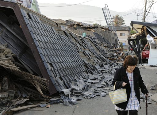 A resident walks past collapsed houses in Mashiki, Kumamoto prefecture, southern Japan, Friday, April 15, 2016, after a magnitude-6.5 earthquake. The powerful earthquake struck Thursday night, knocking down houses and buckling roads. (Ryosuke Uematsu/Kyodo News via AP) JAPAN OUT, MANDATORY CREDIT
