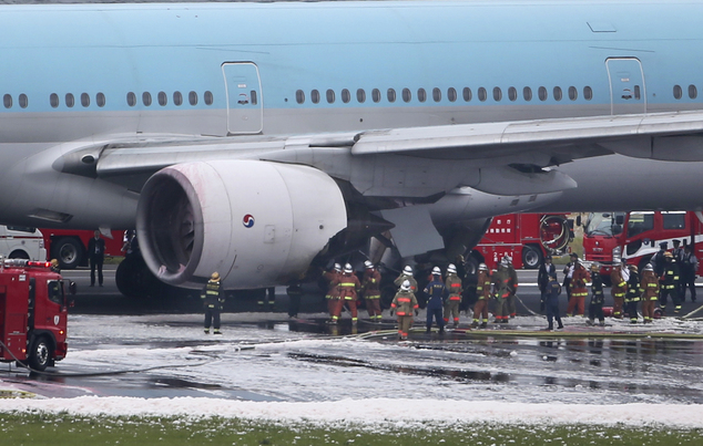 Firefighters work on a Korean Air jet sitting on the white foam-covered tarmac following an engine fire at Haneda Airport in Tokyo Tokyo, Friday, May 27, 2016. The engine fire broke out on the Korean Air jet about to take off from the airport on Friday, and some people may have been injured, an airport official said. Firefighters put out the blaze within the hour, and all passengers and crew were evacuated. (AP Photo/Koji Sasahara)