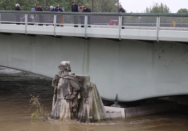 People look at the Zouave statue on the Pont de l'Alma, covered by the rising waters from the Seine River after days of rainy weather in Paris, France, June 2, 2016 as the Zouave statue is considered an indicator of the level of the Seine, when his feet are under water, emergency flood precautions are taken. REUTERS/Pascal Rossignol - RTX2FBUX