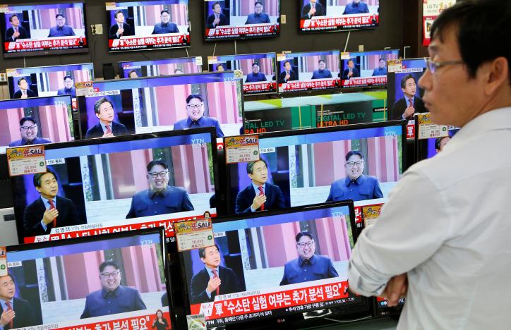 A sales assistant watches TV sets broadcasting a news report on North Korea's fifth nuclear test, in Seoul, South Korea, September 9, 2016. REUTERS/Kim Hong-Ji
