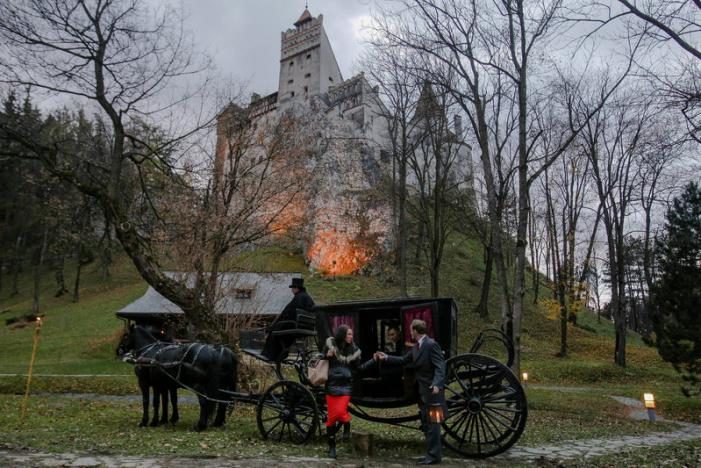 Tami Varma is helped out of a horse-drawn carriage by guide near the northern facade of the Bran Castle, in Brasov county, Romania, October 31, 2016. Inquam Photos/Octav Ganea/via REUTERS